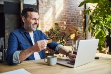 Happy man online shopping through credit card and laptop in an office