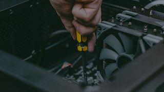 Closeup computer technician holding a screwdriver and repairing a pc