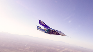 Virgin Galactic's suborbital space plane VSS Unity glides through the skies above New Mexico with mountains visible on the horizon.