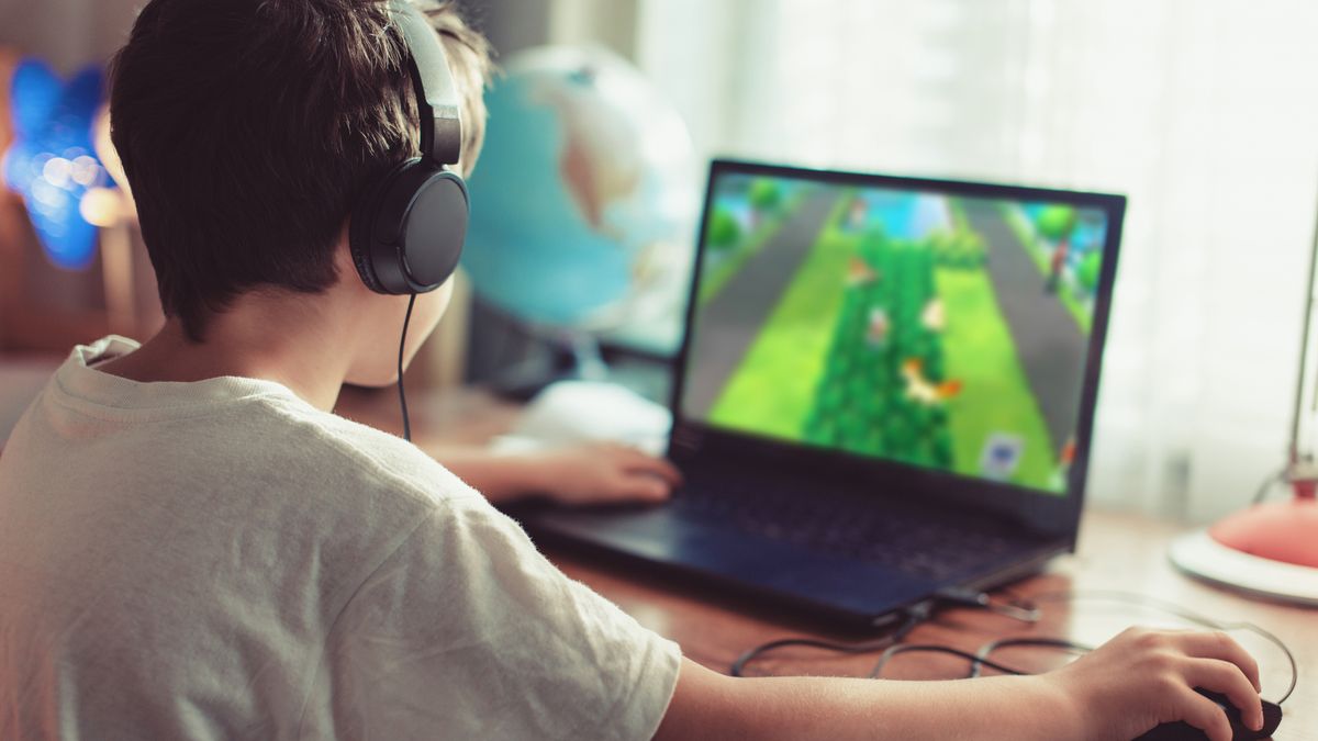 A boy playing a video game on a laptop.