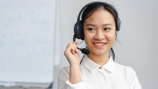 Woman using VoIP headset with high VoIP QoS smiling