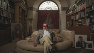 Giancarlo Parrett sitting on his sofa surrounded by movie paraphernalia – subject of The Man Who Definitely Didn’t Steal Hollywood documentary film.