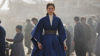 Moiraine walks through a town street in The Wheel of Time season 2