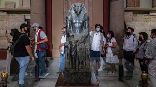 Tourists view the Enthroned Khafre (Chephren) funerary statue of the Fourth dynasty (2613-2494 BC) Ancient Egyptian pharaoh and builder of the second of the Giza Pyramids, on display at the Old Kingdom gallery in the Egyptian Museum in the centre of Egypt's capital Cairo on October 27, 2021. Photo by AMIR MAKAR/AFP via Getty Images.