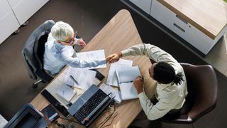 Job interview concept image showing two individuals shaking hands in an office.