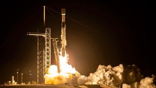 a black and white rocket launches into the night sky from a launch pad in Florida