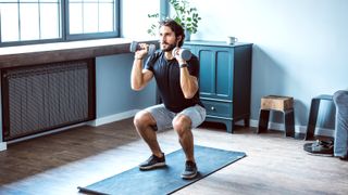 Man performing a dumbbell squat at home