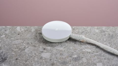 ESR Qi2 Mini Wireless Charger sits on a light grey stone-effect surface against a pink background.