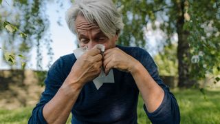 What causes allergies? Image shows man blowing nose