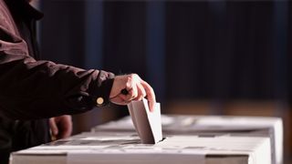 Hand of a person casting a vote into the ballot box during elections