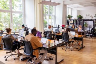 Developers with AI skills working at desks in an open plan office space.