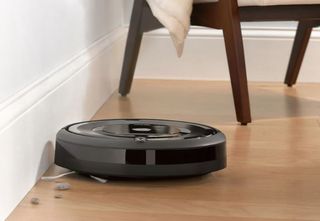 the iRobot Roomba e5 cleaning a hard floor floor with a chair in the background