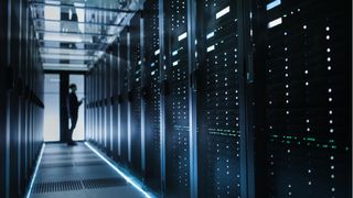 A man standing in front of a rack of servers inside a data center