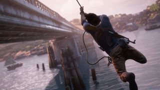 Huvudpersonen i Uncharted 4 svingar sig över vattnet mot en bro.