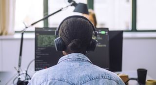 An eBook from IBM on integrating a data lakehouse strategy into your data architecture, with image of back of female in front of a workstation with headphones on