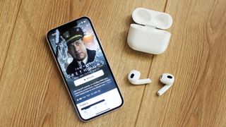 the airpods 3 next to an iphone 13 mini displaying apple tv