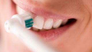 How to use an electric toothbrush: Image shows woman cleaning teeth