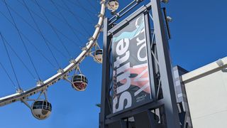 A SuiteWorld sign at Oracle NetSuite's conference, with a ferris wheel and blue sky in the background.