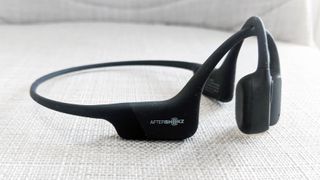 The Shokz OpenRun bone conduction headphones on a grey surface.