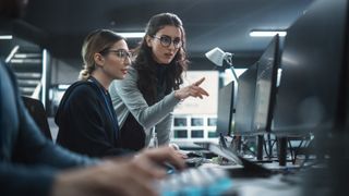 Young Colleagues Working on Computers and Talking at a Workplace