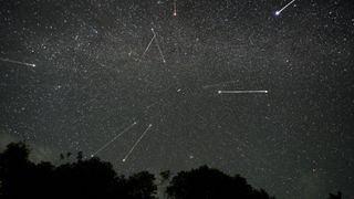 streaks of light crisscross among the stars in the night sky