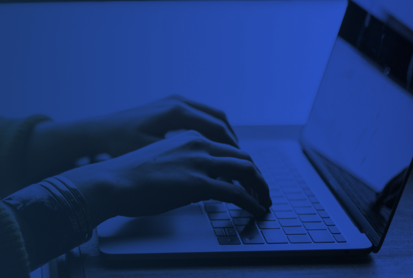 Person typing on a laptop keyboard with dark blue filtered overlay