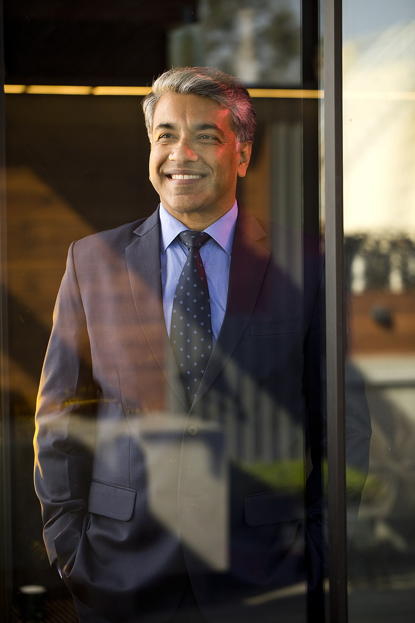 Business man smiling cheerfully while looking out the office window