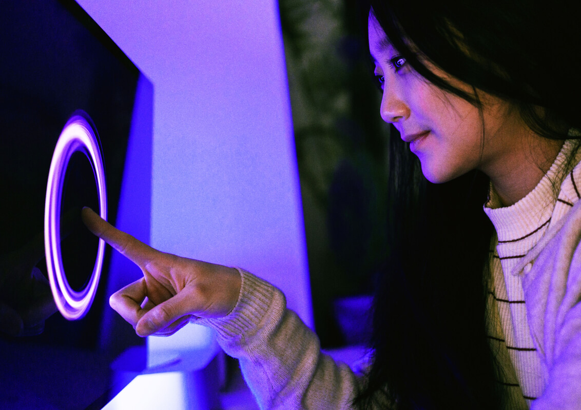 A woman touching a monitor screen