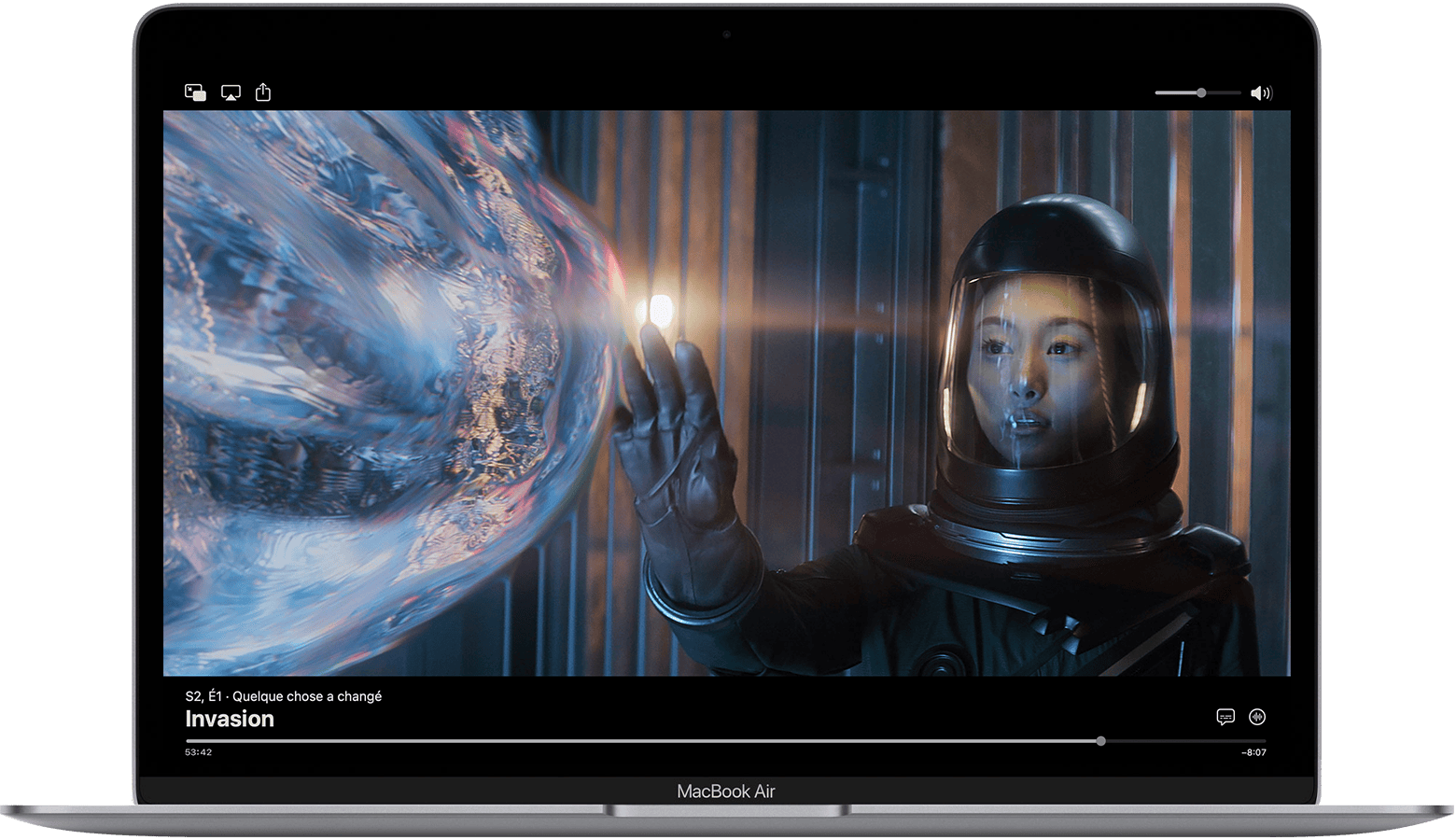 Sur un MacBook Air, l’app Apple TV est mise en pause et les commandes s’affichent. L’épisode est Something's Changed from Invasion. En bas à droite, le bouton Langue des sous-titres et le bouton Audio se trouvent au-dessus de la barre de progression.