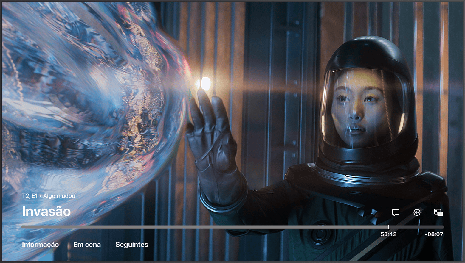 A app Apple TV em pausa com os controlos a ser apresentados. Episódio Algo Mudou da série Invasão. No canto inferior direito, o botão Idioma das legendas e o botão Áudio encontram-se acima da barra de progresso.