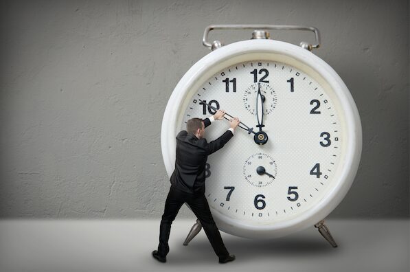 A man pushing an alarm clock on the ground.