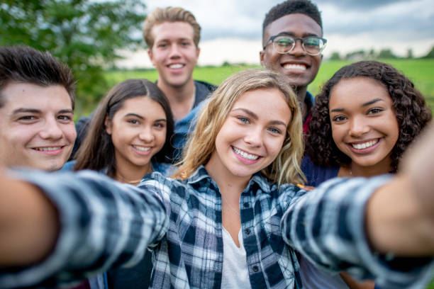 A group of people taking a selfie in the grass.