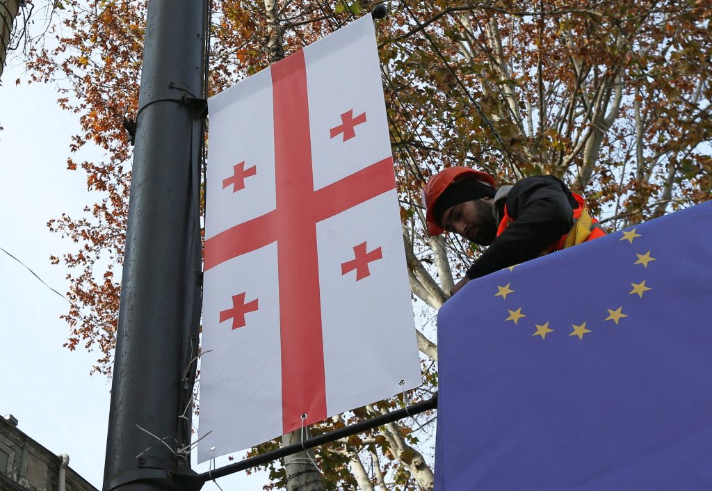 Photo: Worker Goga Akhvlediani hangs a banner with a Georgian flag on a street in Tbilisi, Georgia December 15, 2023. Credit: REUTERS/Irakli Gedenidze