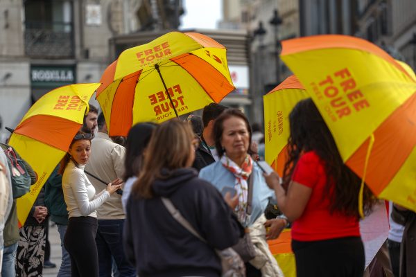 Photo: Tour guides with umbrellas roam the centre of Madrid offering free tours to tourists. Credit: Reuters