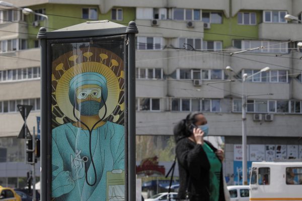 Photo: A woman wearing a medical mask passes by an outdoor poster that shows a medic depicted in a similar manner as Jesus Christ would be portrayed by Christian Orthodox religious paintings, in Bucharest, Romania, April 29, 2020. The poster, created by Romanian illustrator Wanda Hutira, is part of a "Thank you doctors" campaign. Credit: Inquam Photos/Octav Ganea via REUTERS