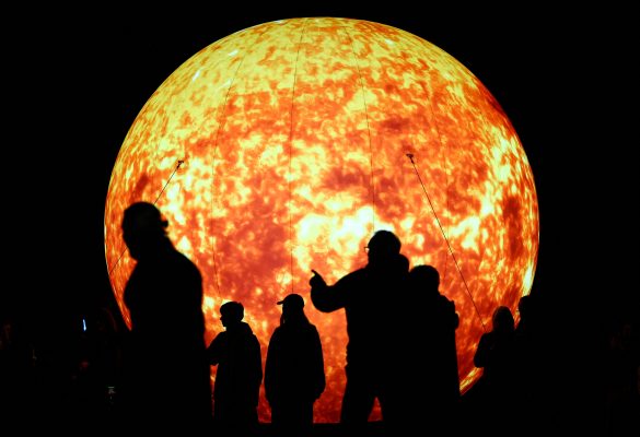 Photo: People are silhouetted as they walk next to an illumination depicting the sun at Humboldt University during the Festival of Lights, in Berlin, Germany October 6, 2023. Credit: REUTERS/Fabrizio Bensch