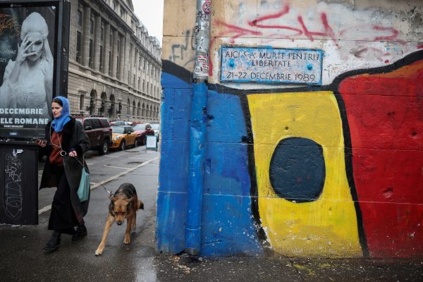 Photo: A woman walks her dog past a mural depicting the Romanian flag, ahead of the runoff for the presidential elections in Bucharest, Romania, December 6, 2024. Credit: REUTERS/Louisa Gouliamaki