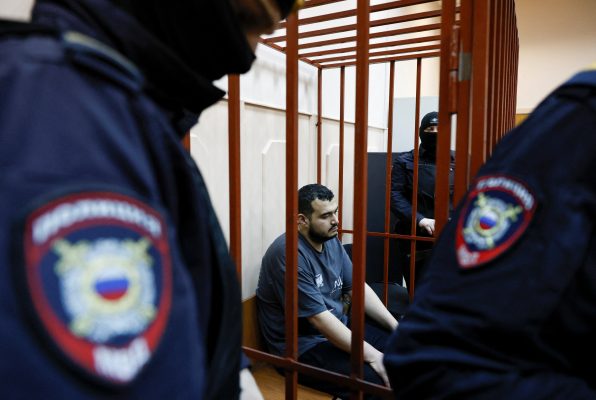 Photo: A detainee, named as Uzbek national Akhmad Kurbanov and considered by investigators as a suspect in the murder of chief of Russia's Nuclear, Biological and Chemical Protection Troops Igor Kirillov along with his assistant, sits inside an enclosure for defendants before a court hearing in Moscow, Russia December 19, 2024. Credit: REUTERS/Yulia Morozova