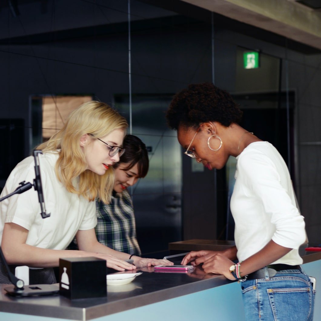 Twee vrouwen bij een balie helpen een nieuwe gast bij het inchecken