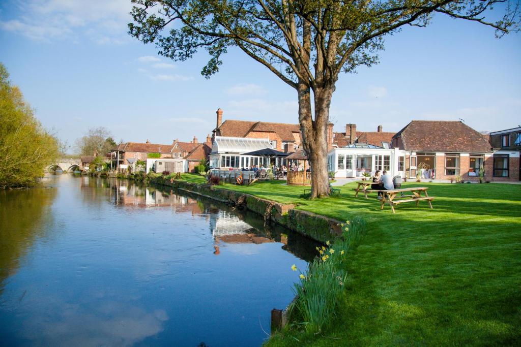 un río en una ciudad con edificios y una persona sentada en un banco en The Legacy Rose & Crown Hotel, en Salisbury