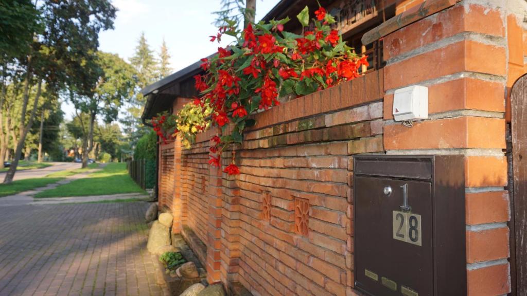 uma parede de tijolos com flores vermelhas em Pas Birute em Kaunas