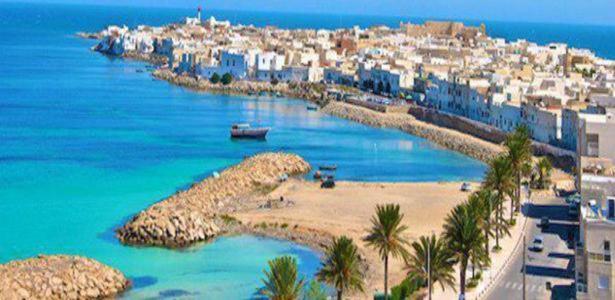 - une vue sur une plage bordée de palmiers et de bâtiments dans l'établissement Houria House Sable D'or, à Mahdia