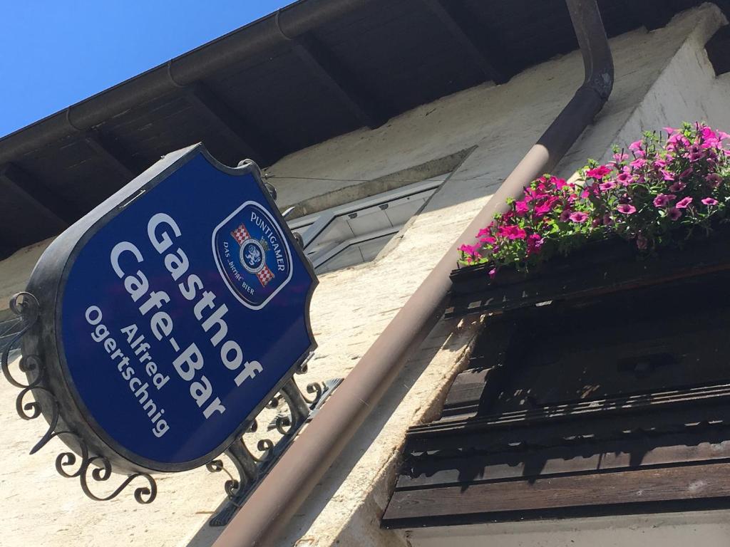 a blue sign on the side of a building with flowers at Gasthof Ogertschnig in Klagenfurt