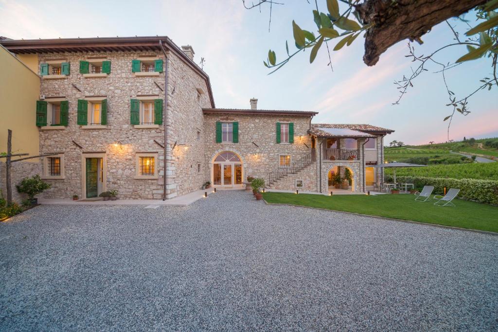 Elle offre une vue sur l'extérieur d'une grande maison en pierre dotée d'une allée. dans l'établissement Corte Formigar, à SantʼAmbrogio di Valpolicella