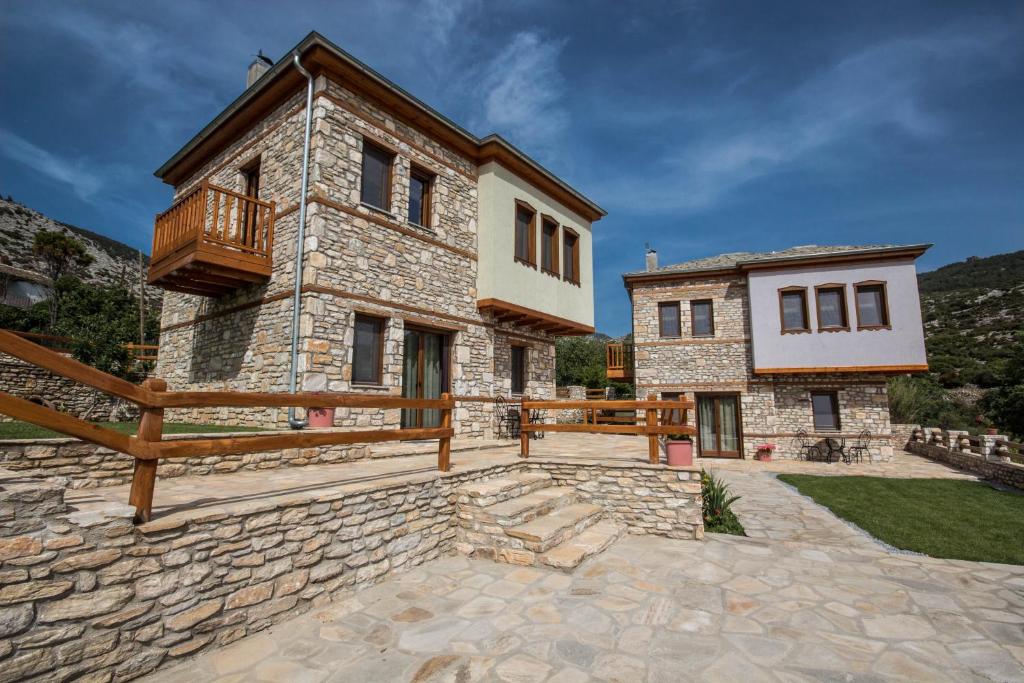 Una gran casa de piedra con un balcón en un lateral. en Harmony Deluxe Villas, en Theológos