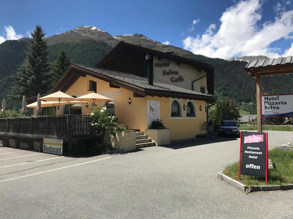 un bâtiment avec un panneau devant lui dans l'établissement Hotel Pizzeria Selva, à Zernez