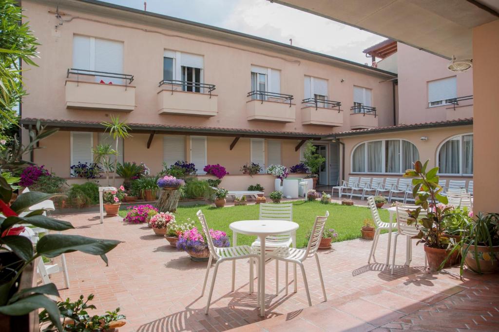 um pátio com cadeiras e uma mesa em frente a um edifício em Hotel Sabrina em Castiglione della Pescaia