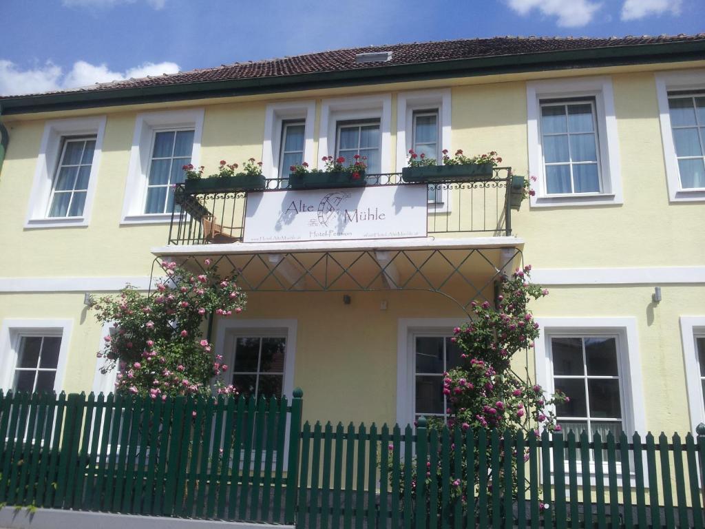 een geel huis met bloemen op de balkons en een hek bij Hotel Pension Alte Mühle in Klosterneuburg