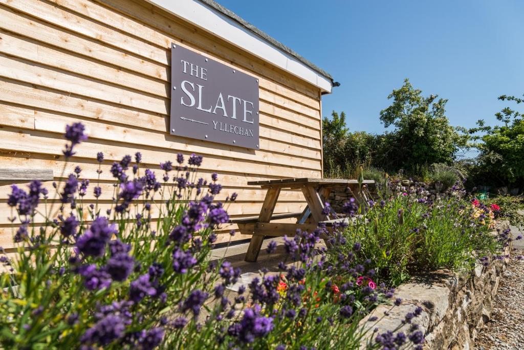 un panneau sur le côté d'un bâtiment avec des fleurs violettes dans l'établissement The Slate, à Bangor