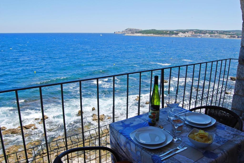 uma mesa com uma garrafa de vinho numa varanda com o oceano em Albatros House em L'Escala